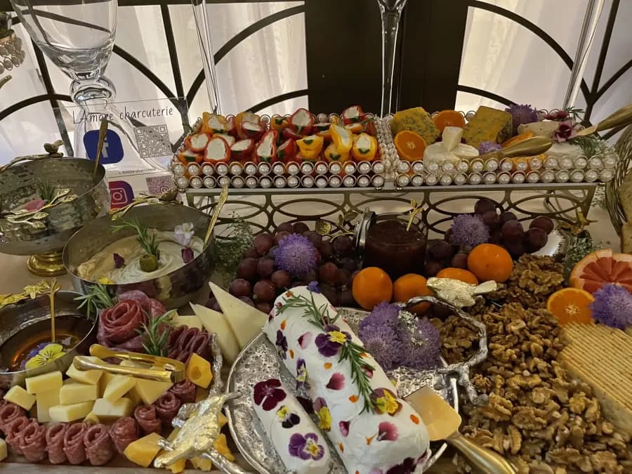 Event table arranged with flowers, fruit, cheese, charcuterie, and small bites