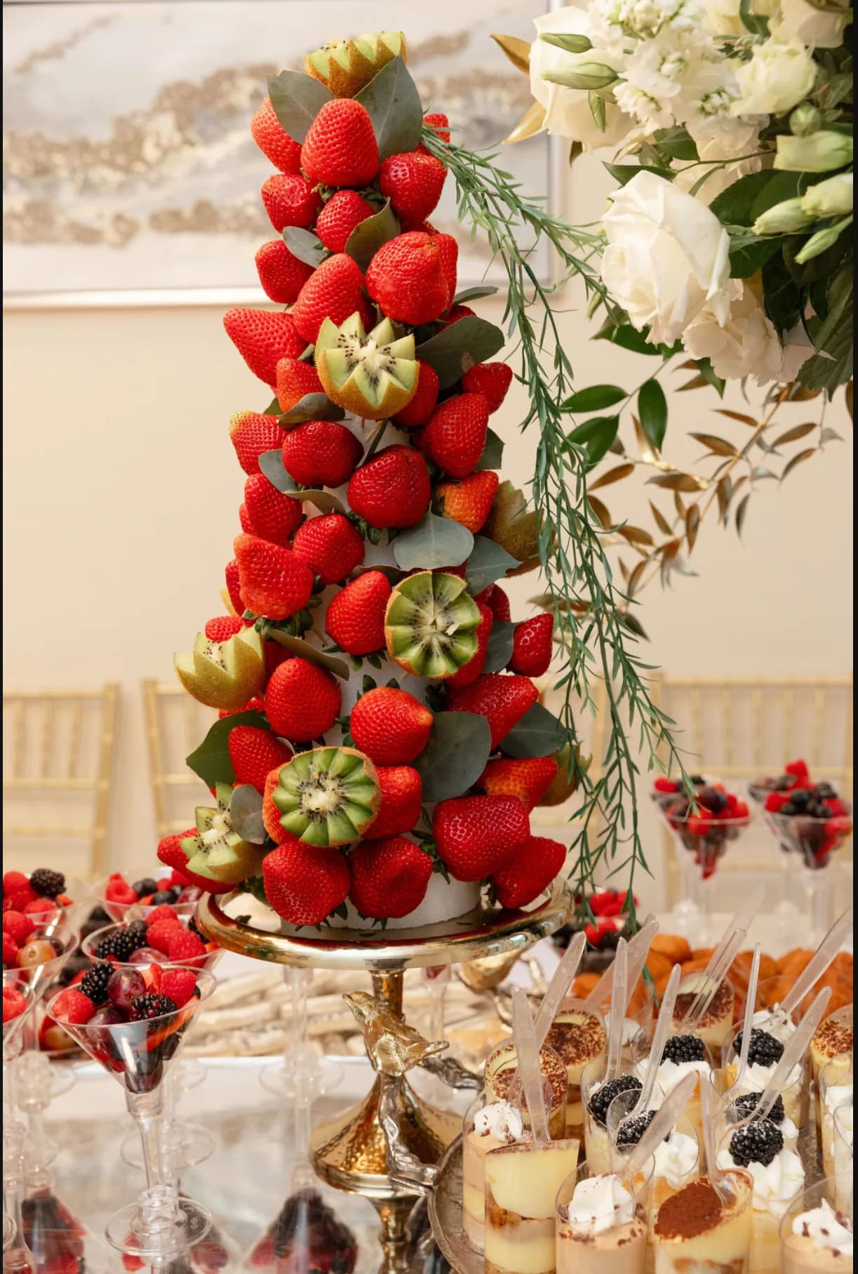 Strawberry and kiwi fruit tower surrounded by individual L’Amore desserts