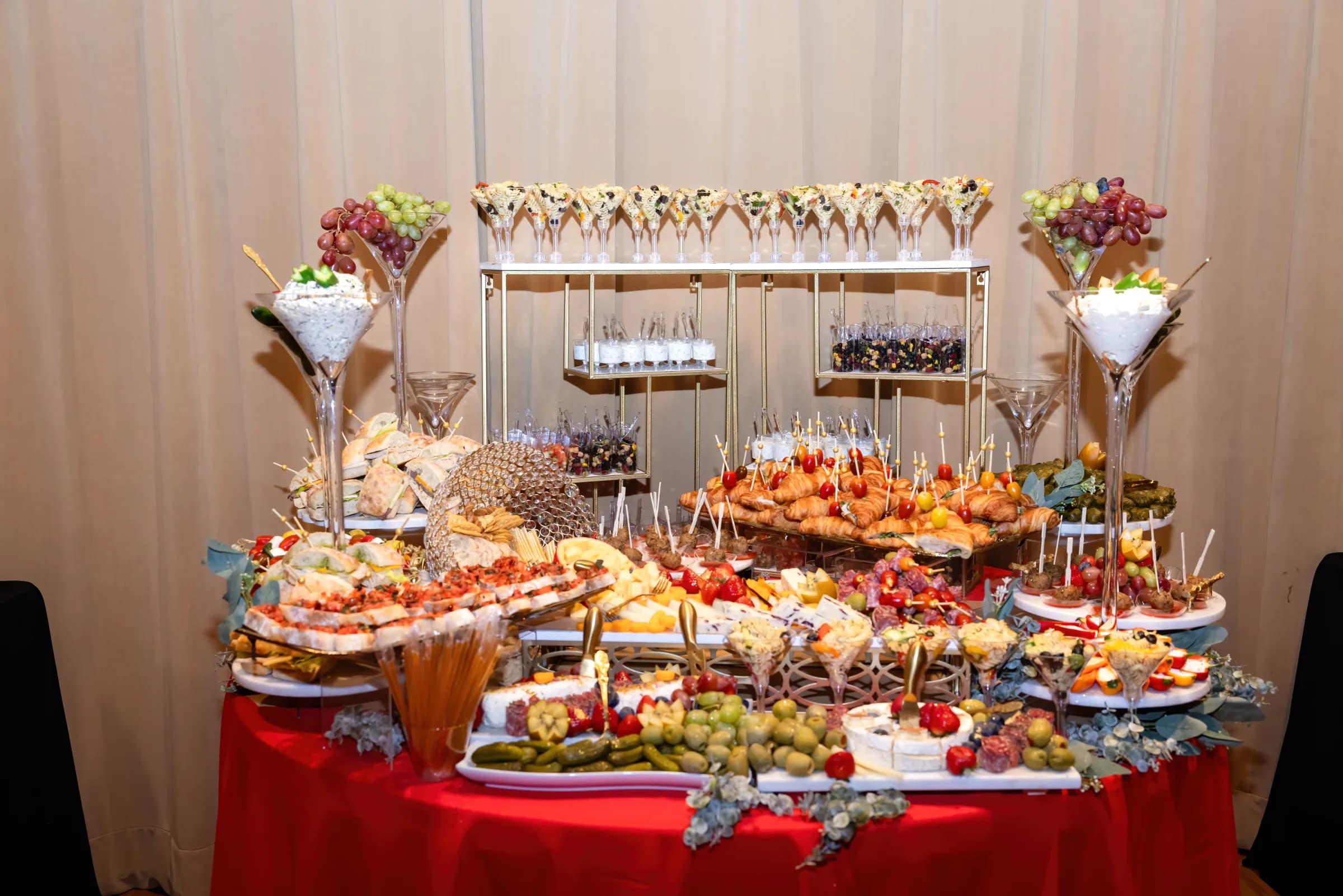 Full grazing and appetizer table with fruit, cheese, sandwiches, and savory bites